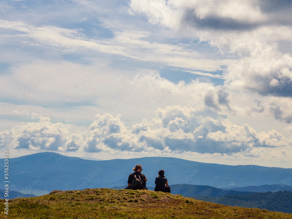  Tourist couple rests on the mountain top with a view. Vacation in the mountains