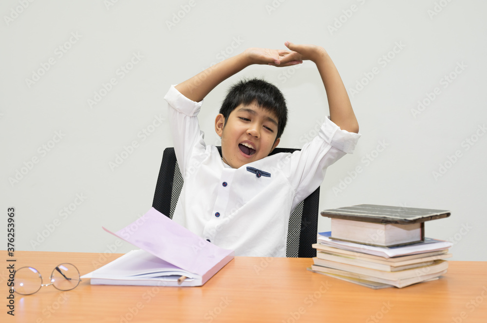 Asian boy student is showing stretch lazily while he is studying in the classroom.A young man stretch oneself during reading a book. Asian boy student is showing stretch lazily while he is studying in the classroom.A young man stretch oneself during reading a book.