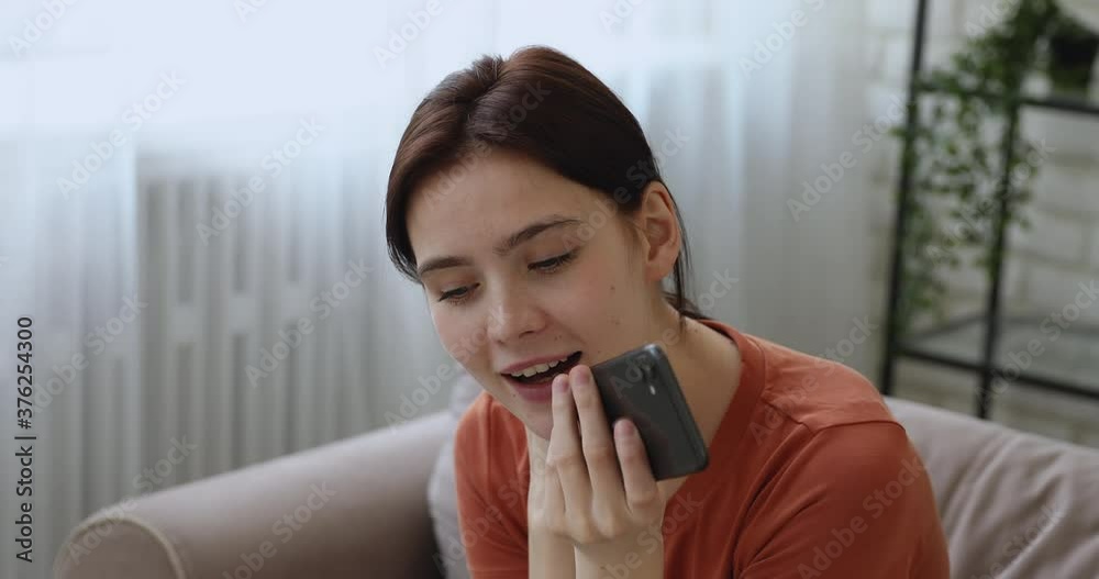 Millennial female sit on couch at home having pleasant personal distant lively conversation on smart phone use speakerphone. Modern technology easy convenient comfortable modern device usage concept Millennial female sit on couch at home having pleasant personal distant lively conversation on smart phone use speakerphone. Modern technology easy convenient comfortable modern device usage concept