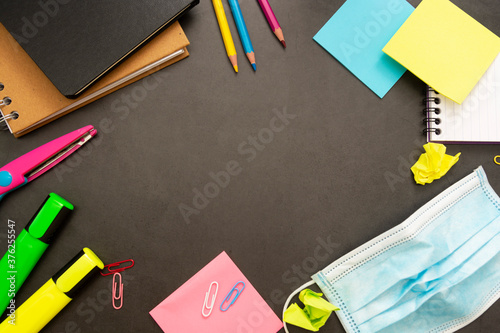 Back to schoolconcept, with colorful office supplies and medical, protective face mask. Education background with copy space. photo