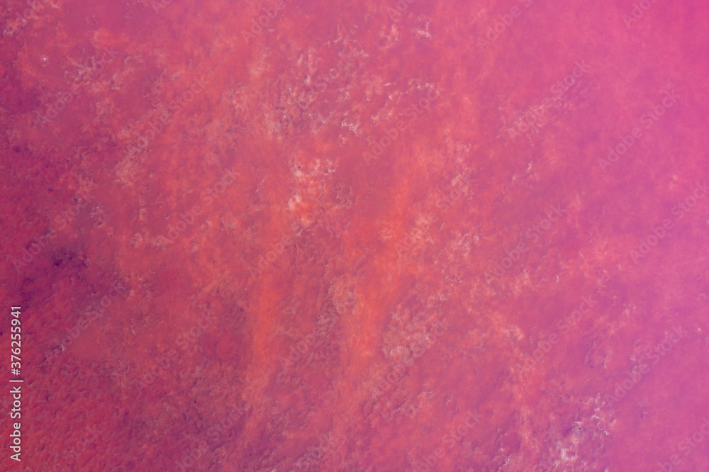 The water surface of a salty reservoir is a rich pink color. Texture. Shooting from a drone. The water surface of a salty reservoir is a rich pink color. Texture. Shooting from a drone.