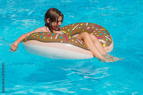 cute girl playing with her inflatable dunut in the pool photo