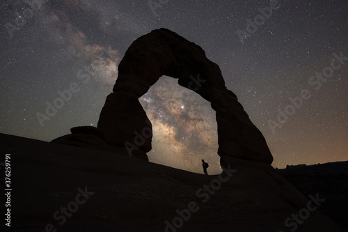 Silhouette of a hiker under Delicate Arch and the Milky Way Galaxy