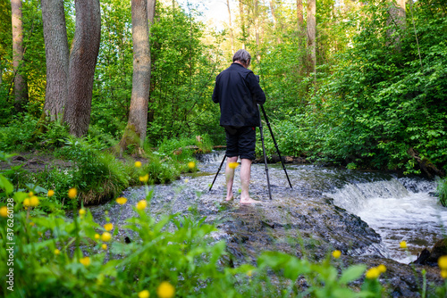 Foto Barefoot photographer taking picture of water cascade while standing in river