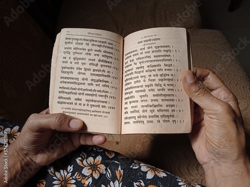 Woman reading old bhagwat Gita in Sanskrit religious book