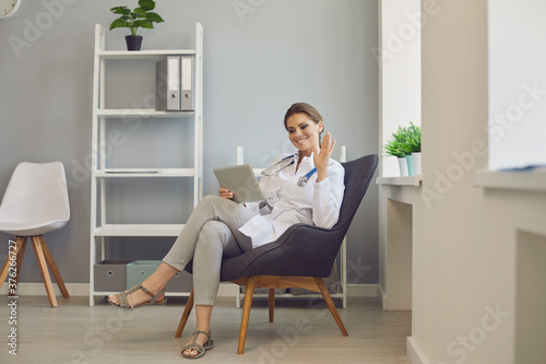 Cybermedicine. Female doctor consulting client on tablet computer from clinic. GP talking to patient online at hospital photo