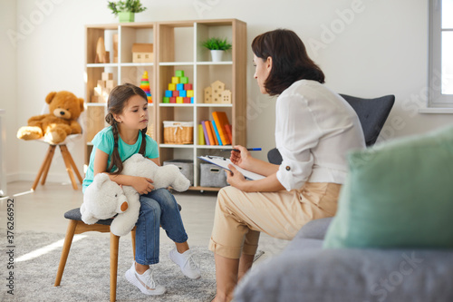Little girl sharing her concerns with supportive child psychologist during therapy session in