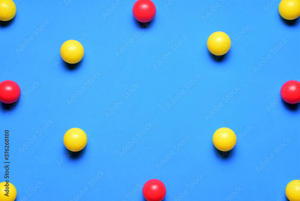 Small colored balls, yellow and red, on a blue background, space for text in the center Small colored balls, yellow and red, on a blue background, space for text in the center