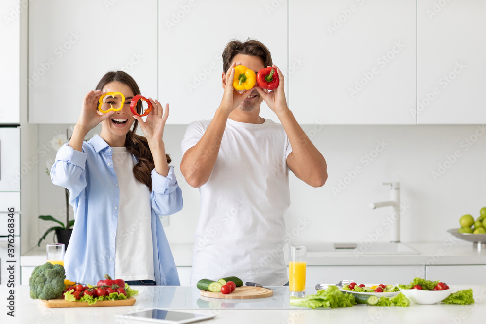 Beautiful young couple having fun while cooking healthy food in kitchen at home. Beautiful young couple having fun while cooking healthy food in kitchen at home.