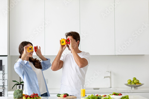 Beautiful young couple having fun while cooking healthy food in kitchen at home.