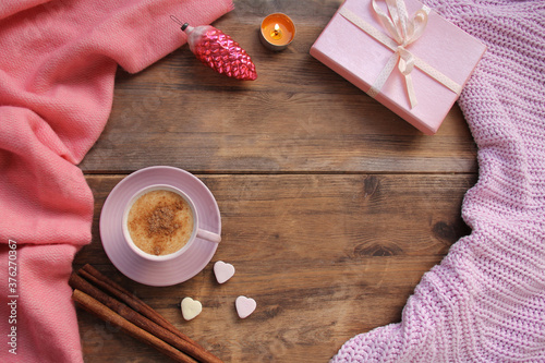 cappuccino with cinnamon in a pink cup, a gift in a box, sweets, candles, cones, Christmas decorations, plaid on an old wooden table, top view, flat, concept cozy home, christmas, copy space