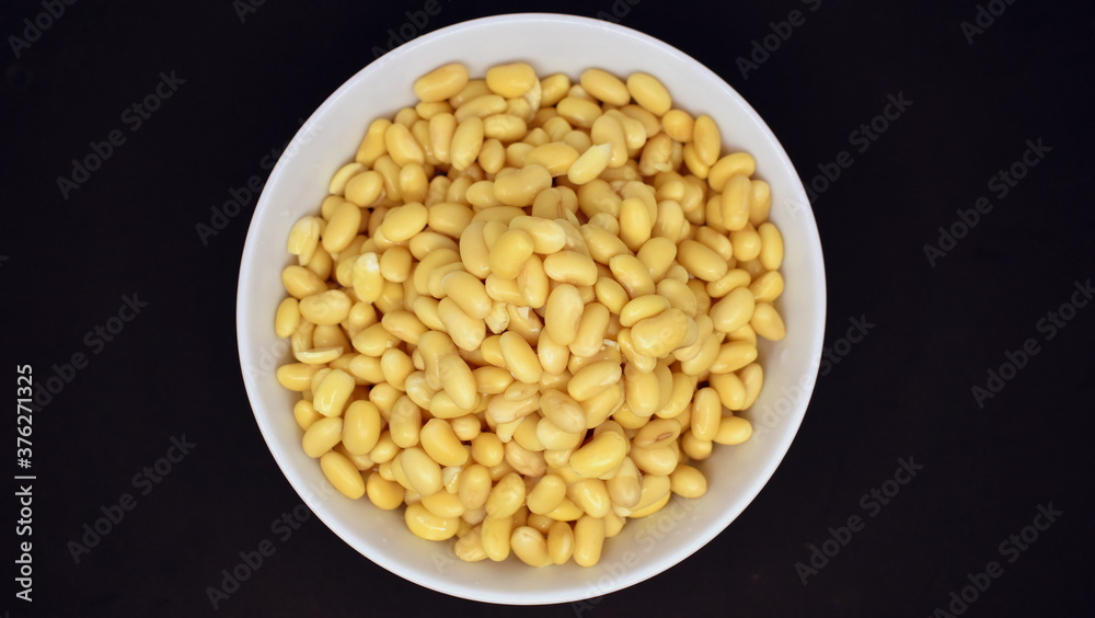 Soybeans after soaking for 24 hours in a bowl on a black background. View from above. Soybeans after soaking for 24 hours in a bowl on a black background. View from above.