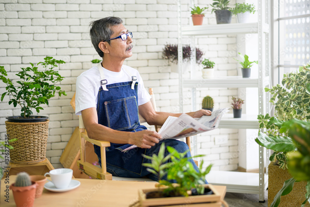 An elderly man is relaxing with coffee and reading Newspaper at his home . An elderly man is relaxing with coffee and reading Newspaper at his home .