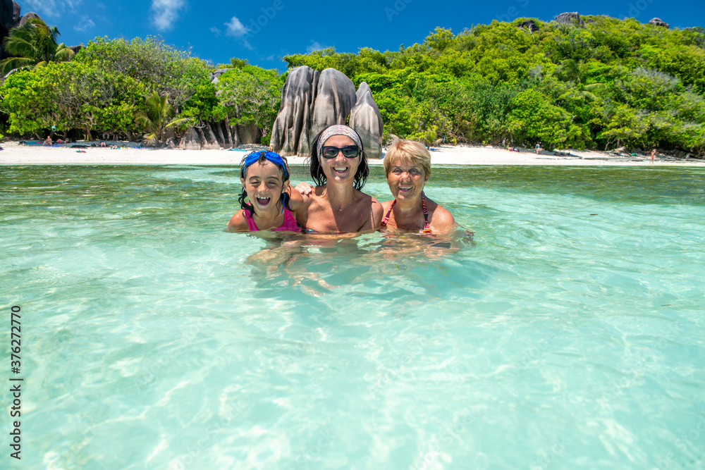 Young girl with mother and grandmother relaxing in the water, Seychelles Islands