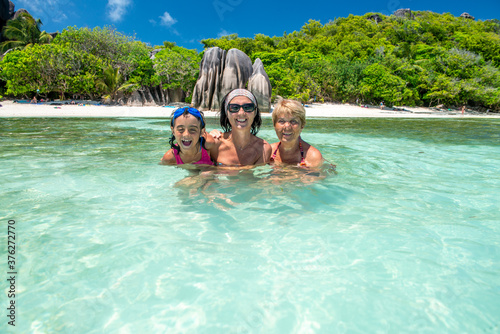 Young girl with mother and grandmother relaxing in the water, Seychelles Islands