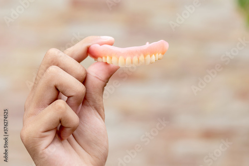 A man is holding dentures in his hands. Removable dentures flexible. False teeth.