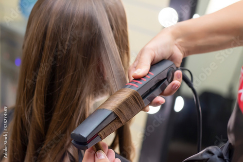 Womens hairdresser, beauty salon. hairdresser makes curls with a curling iron