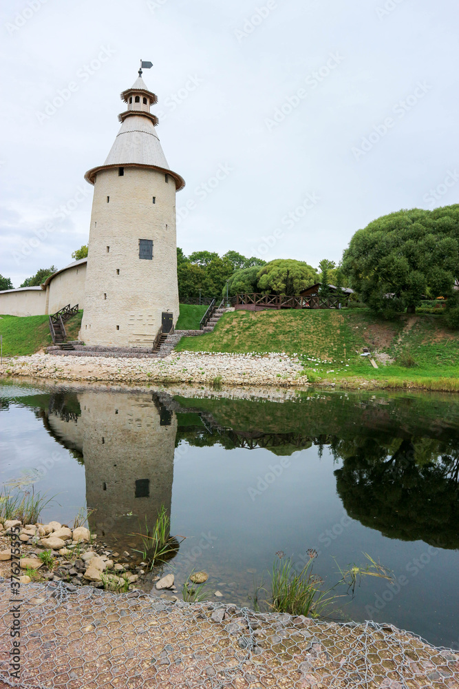 Beautiful view to tall tower of Pskov kremlin (krom) with reflection in water and rivers Pskova and velikaya
