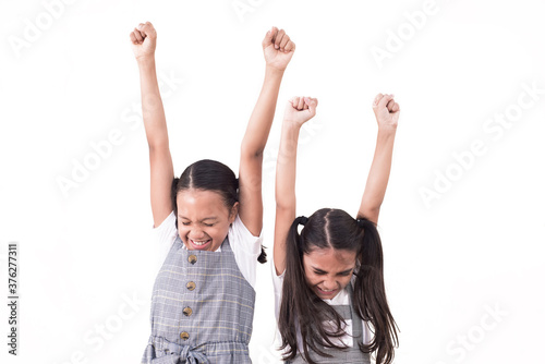 Two little schoolgirls raised their hands up on isolated white background.