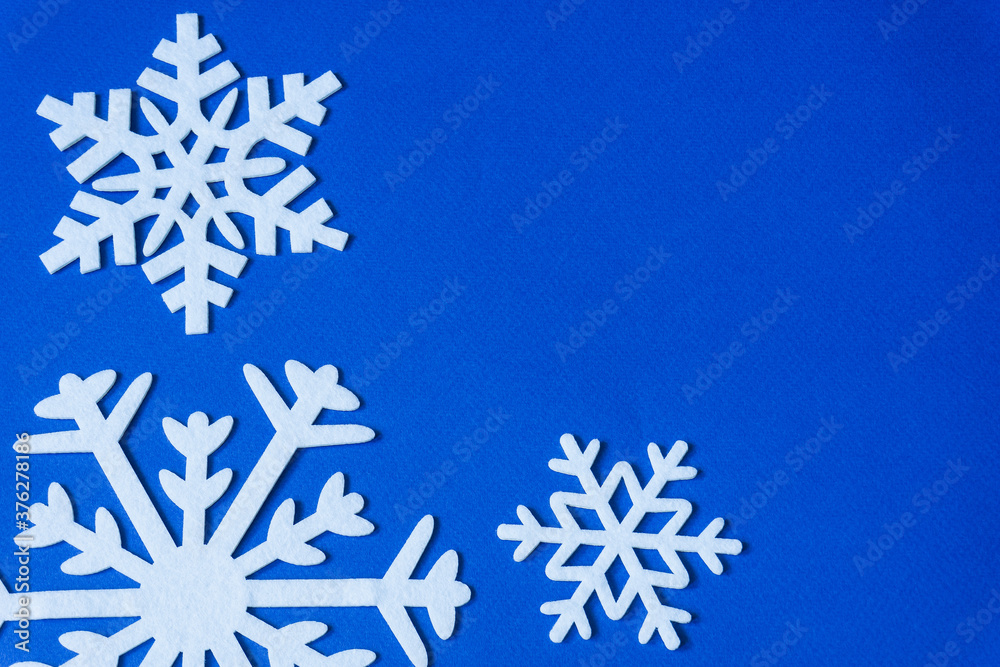 White snowflakes cut from felt on a blue background with copy space. Christmas decoration. White snowflakes cut from felt on a blue background with copy space. Christmas decoration.