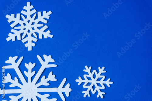 White snowflakes cut from felt on a blue background with copy space. Christmas decoration.