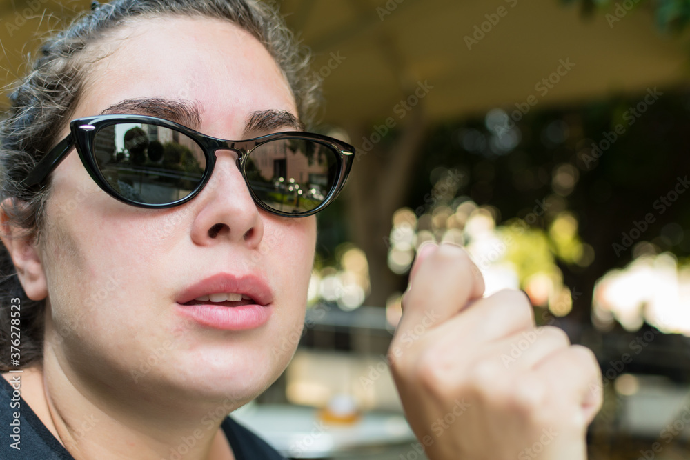 Portrait of young woman with sunglasses, serious, waiting, sitting in an outdoor bar. Portrait of young woman with sunglasses, serious, waiting, sitting in an outdoor bar.