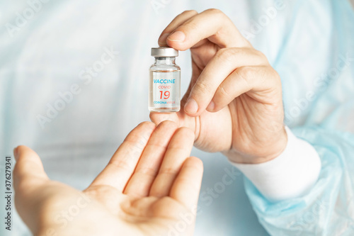 Vial with new usa, american vaccine for covid-19 coronavirus, flu, infectious diseases. Hand reaches to doctor. Injection after clinical trials for vaccination of human, people. Medicine,drug concept