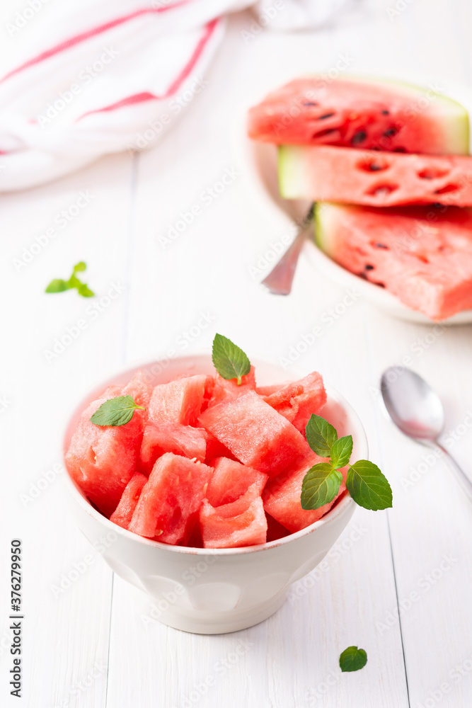 Juicy ripe sweet red watermelon slices with mint leaves in a bowl on a white background, delicious summer berries Juicy ripe sweet red watermelon slices with mint leaves in a bowl on a white background, delicious summer berries