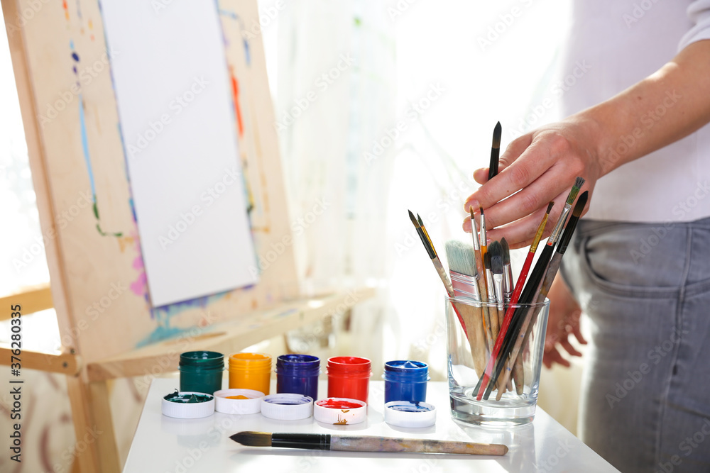 painter's hand holds brush on the background of the easel painter's hand holds brush on the background of the easel