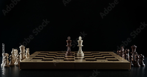 chess pieces on chessboard on black background Fototapeta