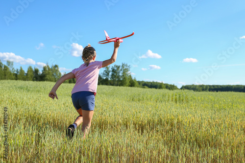 cheerful child plays with styrofoam plane in the summer field 