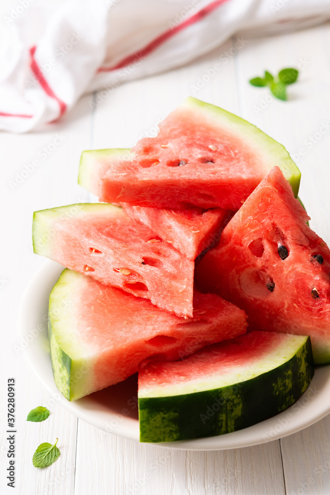 Juicy ripe sweet red watermelon slices with mint in a plate on a white background Juicy ripe sweet red watermelon slices with mint in a plate on a white background
