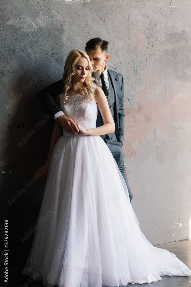 Cute wedding couple in interior of classic studio. They kiss and hug each other. Cute wedding couple in interior of classic studio. They kiss and hug each other.