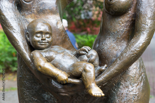 Sculpture of a happy sleeping child in the arms of parents. Monument to family and children.