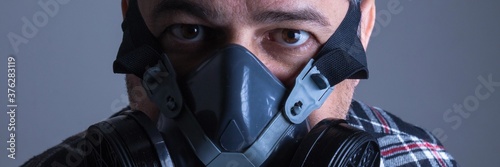 Adult white man in plaid blouse with gas protection mask looking suspiciously photo