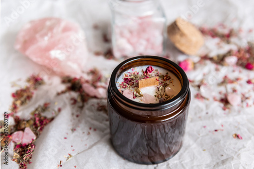 Handmade ecological candle on a white background with dried flowers and rose quartz.