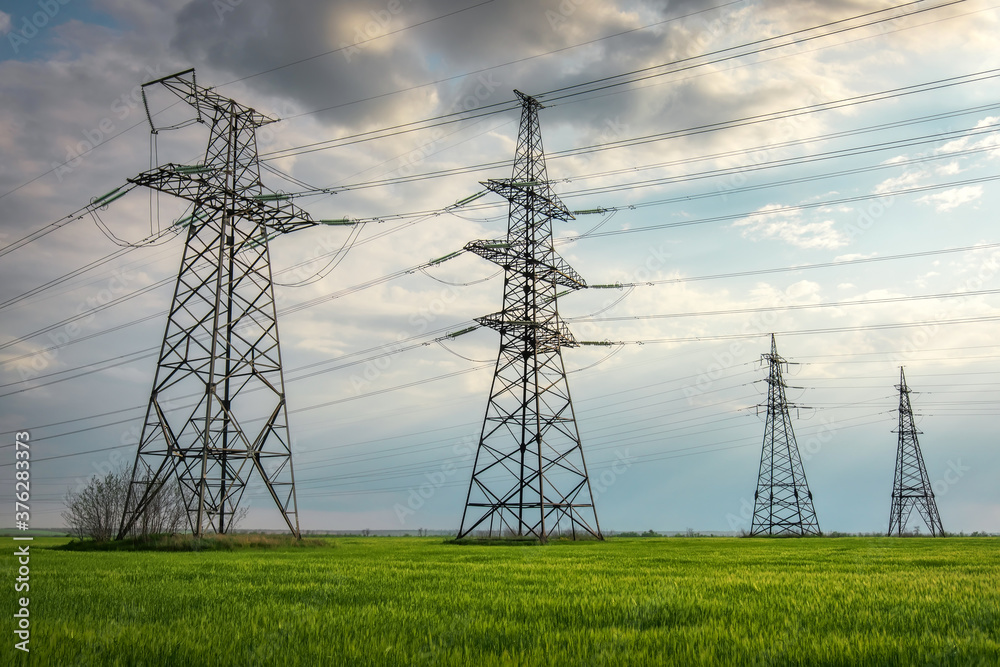 High voltage lines and power pylons in a flat and green agricultural ...