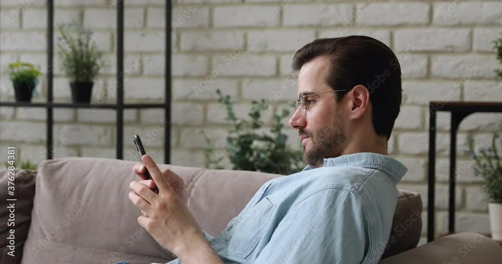 35s man feels carefree enjoy free time sit leaned on sofa in living room alone with smartphone smiling spend weekend using social media web virtual communication, having fun relaxing at home concept 35s man feels carefree enjoy free time sit leaned on sofa in living room alone with smartphone smiling spend weekend using social media web virtual communication, having fun relaxing at home concept