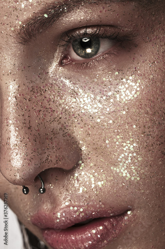 Portrait of beautiful woman with art glitter makeup on her face,