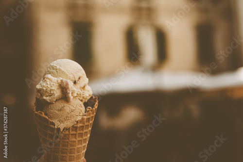 Coffee-vanilla ice cream in crispy waffle cone. Side view with copy space. Sweet dessert closeup. 