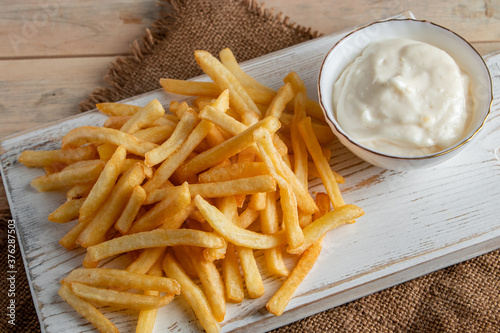 Hot golden french fries with sauce on wooden background. Homemade rustic food.