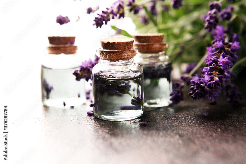 Glass bottle of Lavender essential oil with fresh lavender flowers for healthy aromatherapy spa massage concept on table Glass bottle of Lavender essential oil with fresh lavender flowers for healthy aromatherapy spa massage concept on table