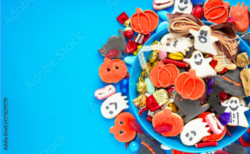 Halloween Jack o Lantern candy bowl with candy and halloween cookies Trick or Treat on blue background