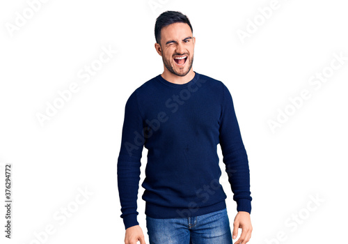 Young handsome man wearing casual clothes winking looking at the camera with sexy expression, cheerful and happy face.