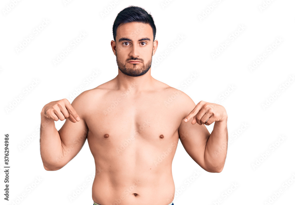 Fototapeta premium Young handsome man wearing swimwear pointing down looking sad and upset, indicating direction with fingers, unhappy and depressed.