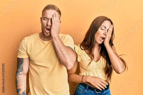 Young couple of girlfriend and boyfriend hugging and standing together yawning tired covering half face, eye and mouth with hand. face hurts in pain.