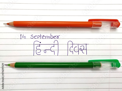 14 September hindi divas concept with orange and green pen on book's paper. Translate: