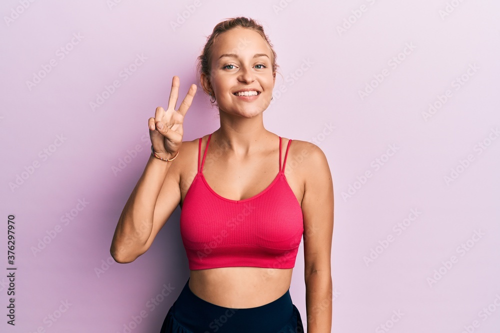 Beautiful caucasian woman wearing sportswear showing and pointing up with fingers number two while smiling confident and happy. Beautiful caucasian woman wearing sportswear showing and pointing up with fingers number two while smiling confident and happy.