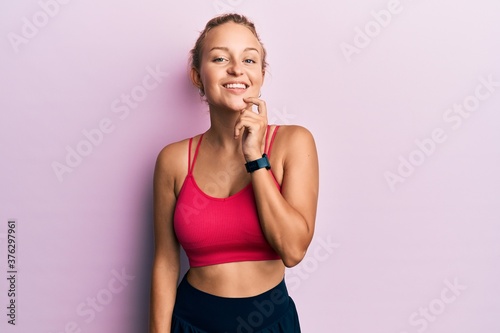 Beautiful caucasian woman wearing sportswear looking confident at the camera with smile with crossed arms and hand raised on chin. thinking positive. © Krakenimages.com