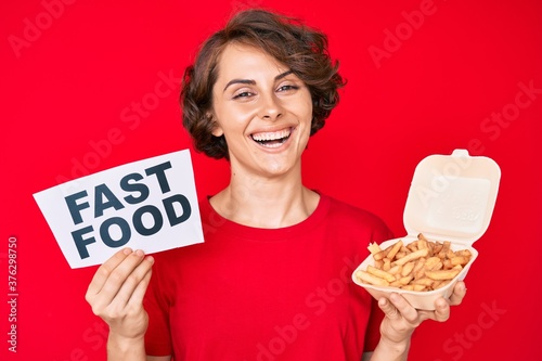 Young hispanic woman holding potato chip and fast food banner smiling with a happy and cool smile on face. showing teeth.